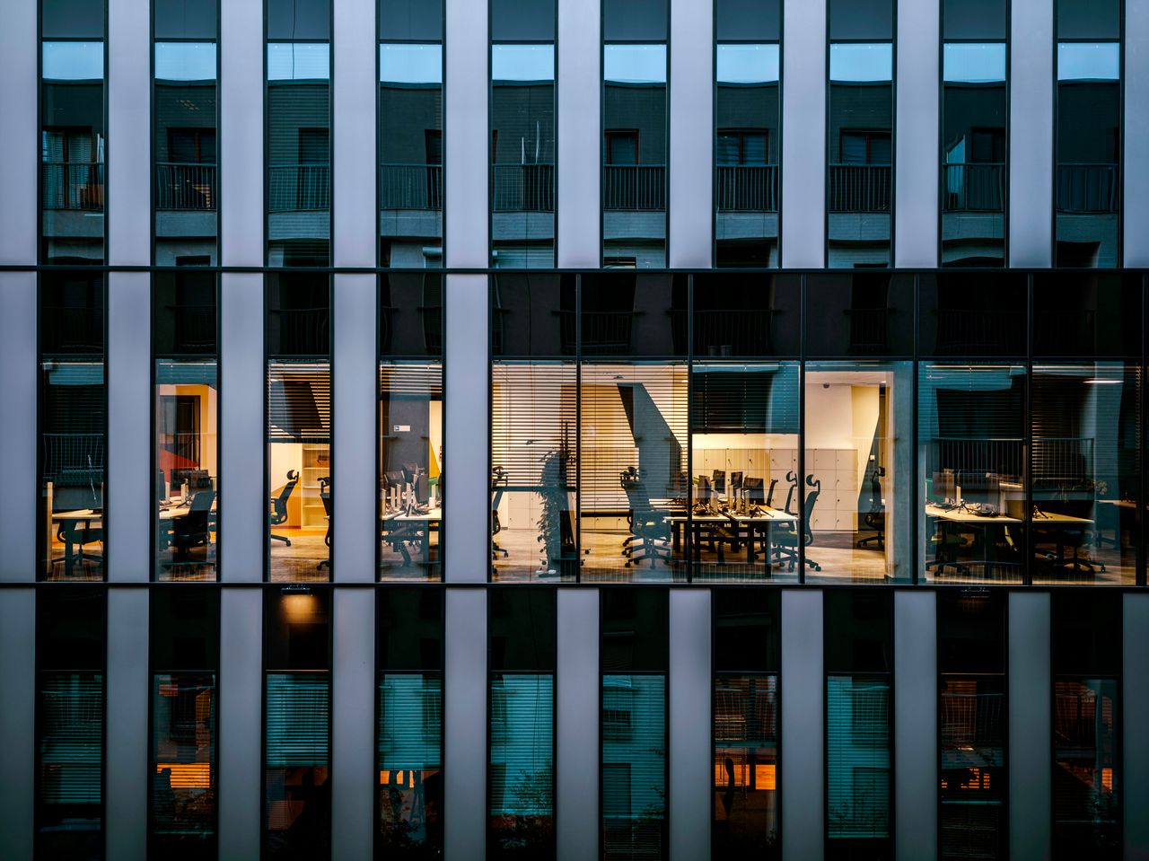 services-03 Illuminated office inside a modern glass building exterior, showcasing architecture and workspace design.